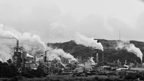 Smoke emitting from factory against sky