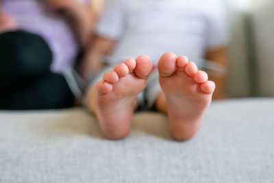 Low section of baby lying on bed