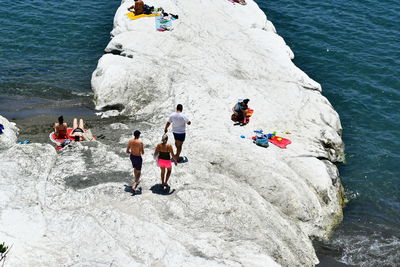 High angle view of people on rock by sea