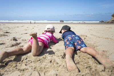 Rear view of women at beach against sky