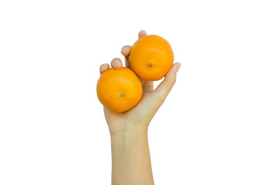 Close-up of hand holding orange against white background