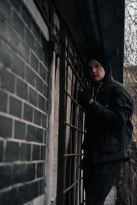 Portrait of young man standing against brick wall