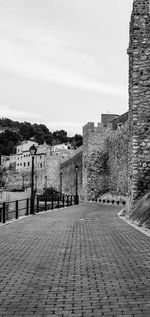 Footpath amidst buildings in city against sky