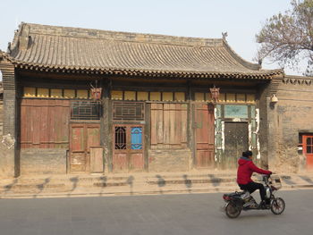 Man cycling on bicycle against building