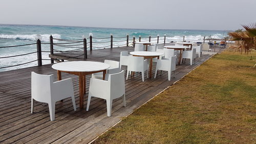 Chairs and table on beach against sky