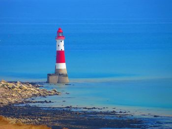 Lighthouse by sea against sky