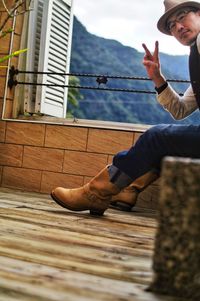 Side view of man sitting on wooden wall