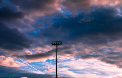 Low angle view of electricity pylon against dramatic sky