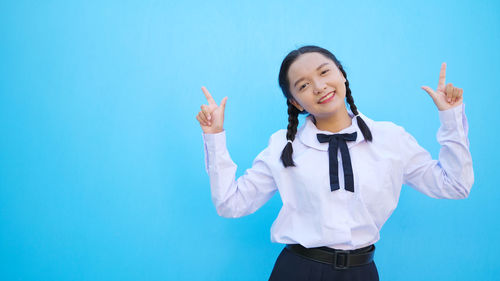 Portrait of a smiling young woman standing against blue sky