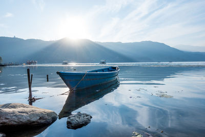 Boats moored on lake against sky