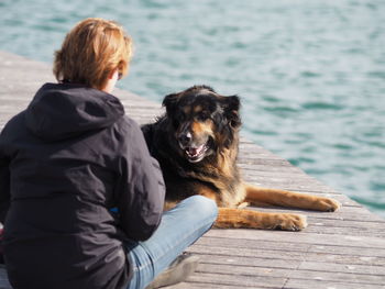 Rear view of girl with dog sitting on porch