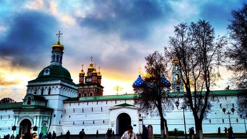 Tourists in front of church against sky during sunset