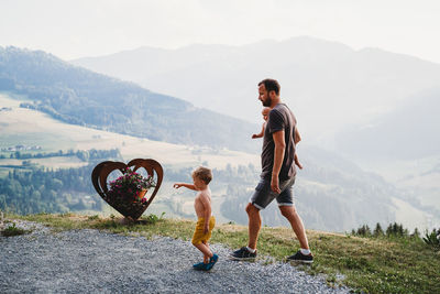 Father and sons walking by the mountains in the summer