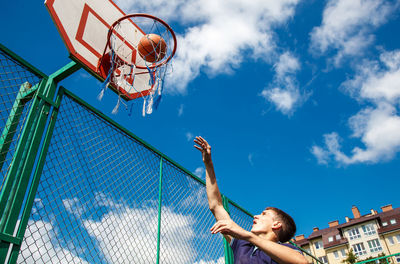 Low angle view of man playing basketball against sky