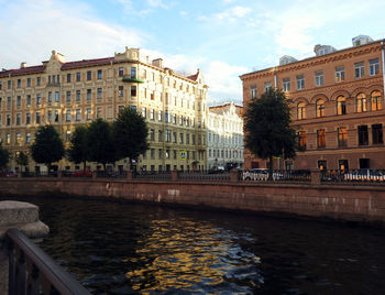 Buildings by canal against sky in city