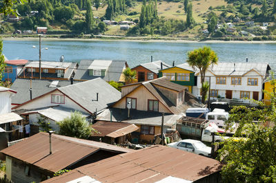 High angle view of houses by river against buildings