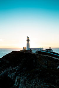 Lighthouse by sea against sky