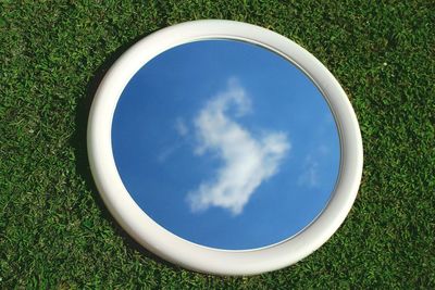 Reflection of sky and clouds in mirror on grass