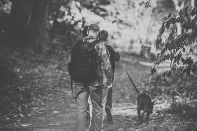 Rear view of people with dog walking in forest