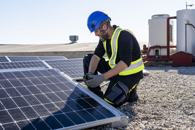 Technician examining solar panels on sunny day