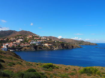 Scenic view of town by sea against blue sky