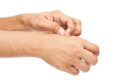 Cropped image of person scratching hand against white background