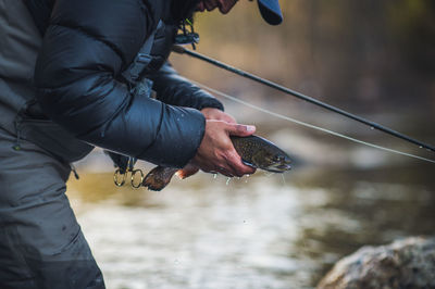 A man releases a trout during a cold morning on a maine river