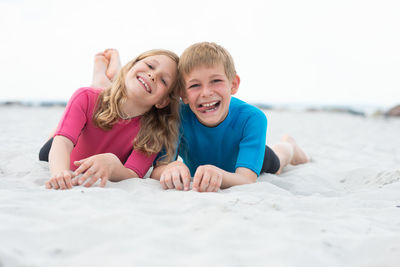 Happy friends enjoying at beach against clear sky