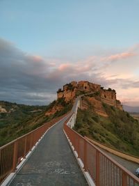 Road leading towards mountain against sky during sunset