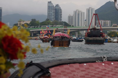 Boats in river by buildings against sky