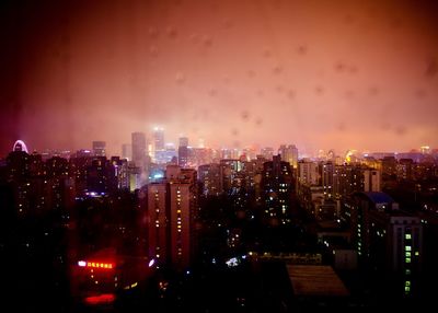 Illuminated cityscape against sky at night