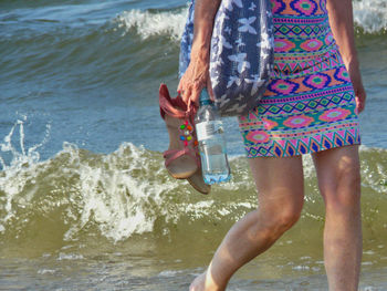 Low section of man holding umbrella on beach