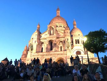 Group of people outside temple against blue sky