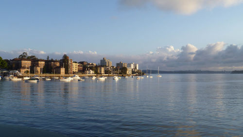 Sea by buildings in city against sky