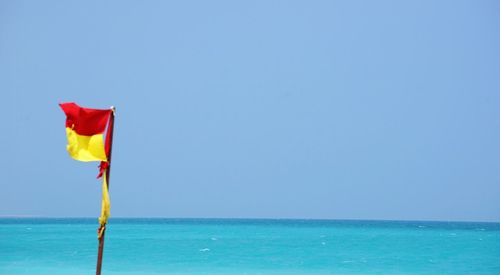 Signal flag at beach by sky and sea