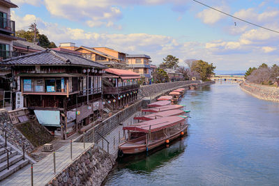 Scenic view of river by buildings against sky