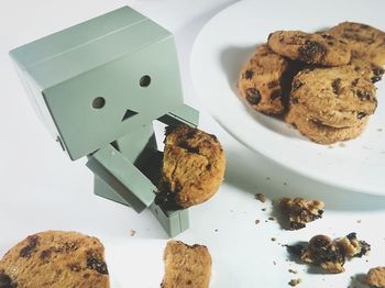 Close-up of toy and cookies in plate over white background