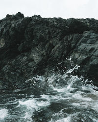 Rock formation by sea against sky