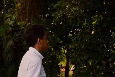 Side view of boy against trees