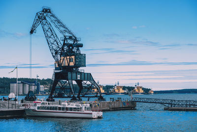 Cranes at commercial dock against sky