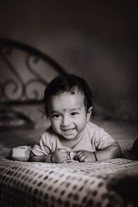 Cute baby boy smiling while lying on bed at home