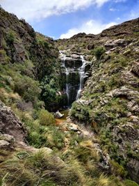 Scenic view of waterfall against sky