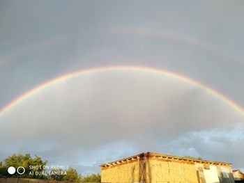 Low angle view of rainbow over building against sky
