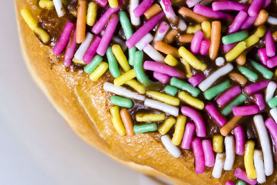 Close-up of multi colored candies on quarter of a donut