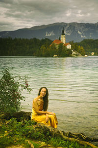 Woman in yellow dress sitting on the shores of lake bled, slovenia iii