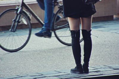 Low section of woman standing at sidewalk