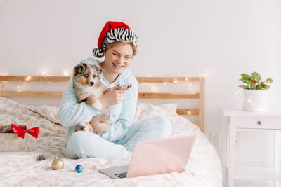 Portrait of smiling woman with dog sitting against wall