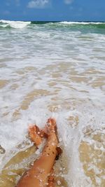Low section of person on beach against sky