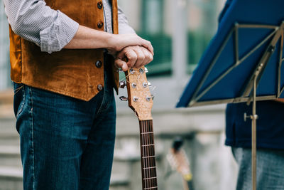 Midsection of man standing with guitar on stage