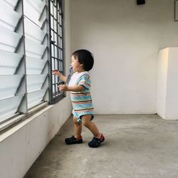 Side view of boy standing against wall